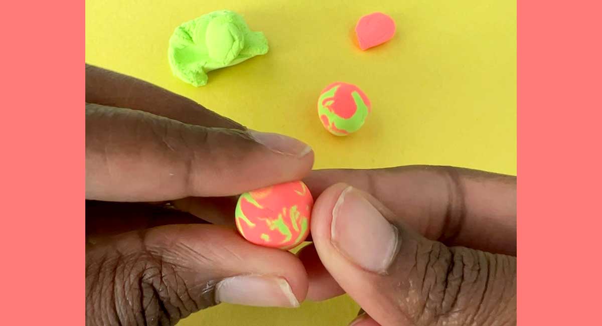Image of a pair of hands making beads from clay